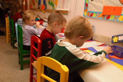 Many children drawing pictures in a kindergarten class