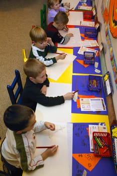 Many children drawing and having fun together in their kindergarten class