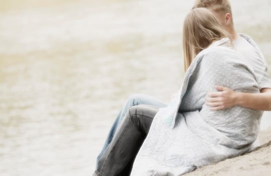 Blanket wrapped around couple on beach