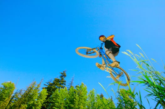 Mountain biker in air against blue sky