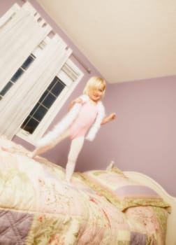 Young girl jumping on bed