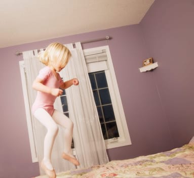 Young girl jumping on bed