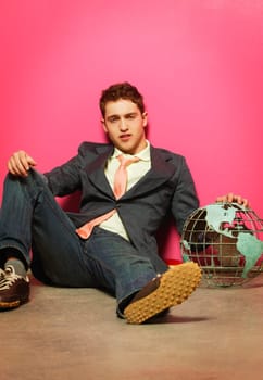 young man with globe sprawled against a wall