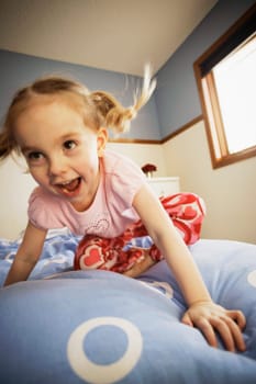 Young girl bouncing on bed