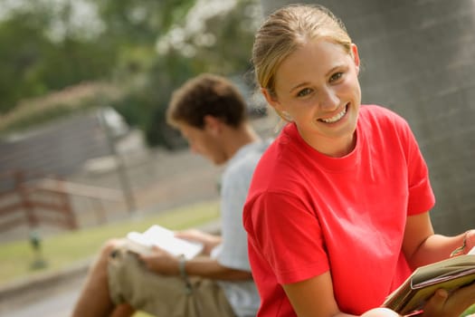 Smiling student reading outside