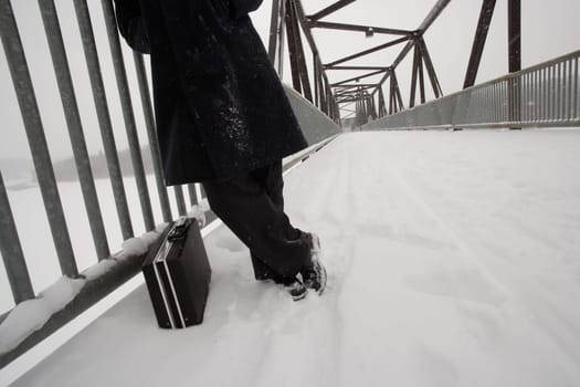Man with briefcase waiting on snow covered bridge