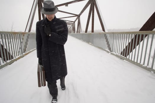 Businessman walking across a snow covered bridge