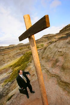 Businessman looking at watch standing at cross