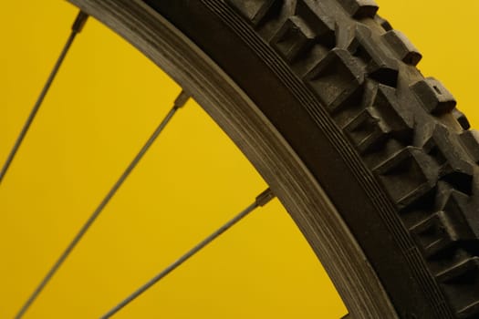 Part of a bicycle wheel against a yellow background