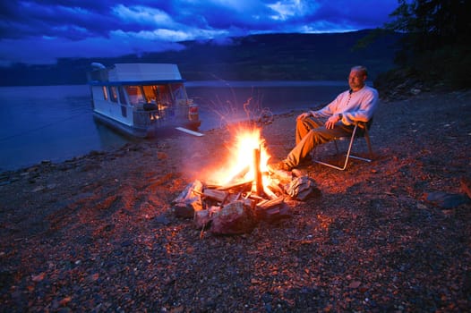 Man on shore relaxing at campfire