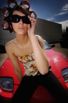 A young woman sitting on the hood of a sports car