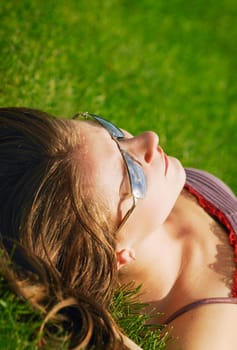 A young woman sunbathes on the grass