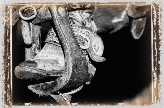 A black and white photo of a cowboy boot and stirrup