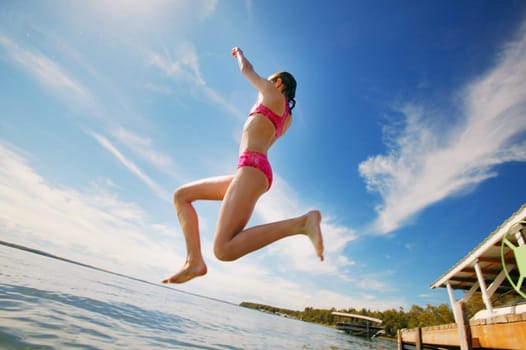 A teenage girl jumping into a lake