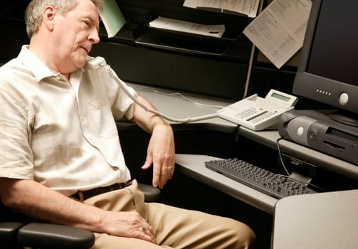 A senior businessman on the phone at his desk