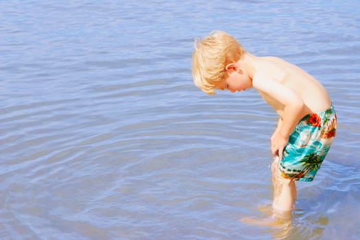A young boy wading in water