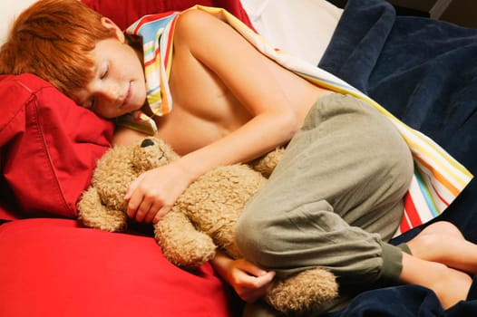 Young super hero sleeping with teddy bear