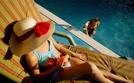 Boy spraying woman sunbathing