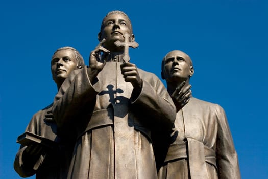Statue of men holding cross and book
