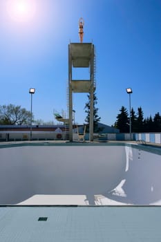 A woman preparing to dive into an empty swimming pool