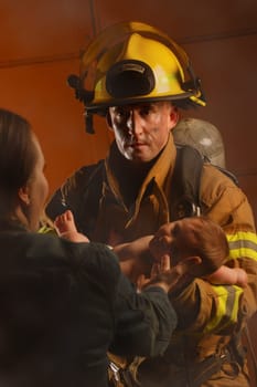Fire fighter passing baby to mother