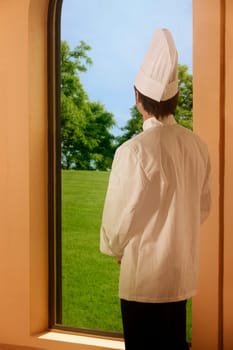 A chef looking outside a window