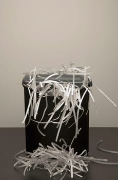 An overflowing garbage can of shredded paper