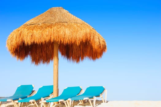 Palm hut and chairs on tropical beach