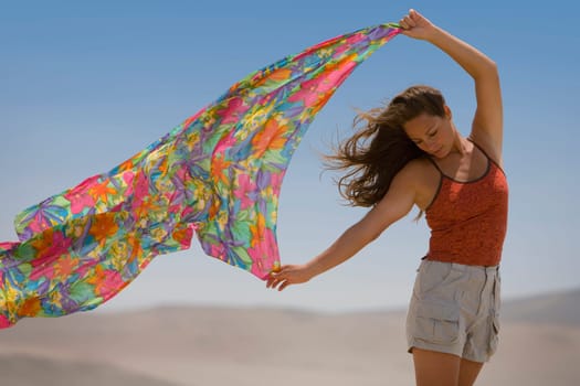 A woman holds out a scarf in the wind