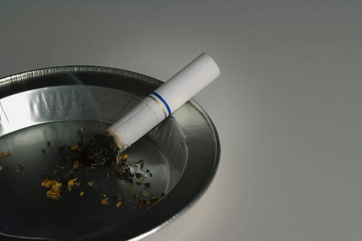 Smoldering cigarette in ashtray