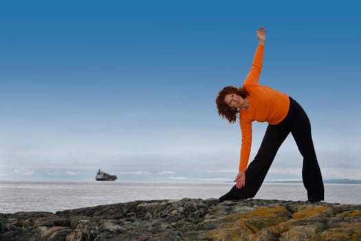 Woman stretching on a rocky beach
