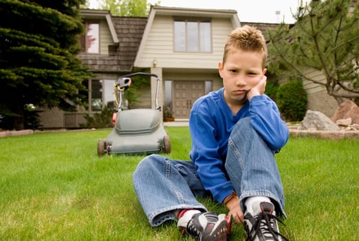 A boy sulks and avoids mowing the lawn