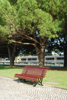 Wooden bench on a park and a train passing (behind)