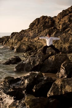 A man stretching on a rocky beach in Koh Lanta,Thailand