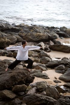 A man stretching on a rocky beach in Koh Lanta,Thailand