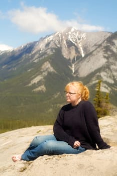 Young woman sitting in the mountains, Jasper, Canada