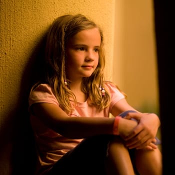 Girl sitting by a wall