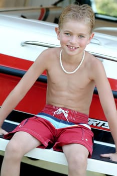 Boy sitting on boat wearing bathing suit