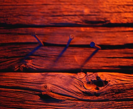 Three nails in wood in red tones