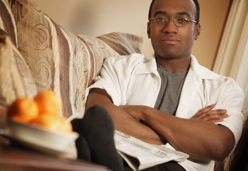 Man reading newspaper on sofa