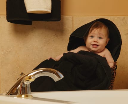 Baby wrapped in towel in bathroom