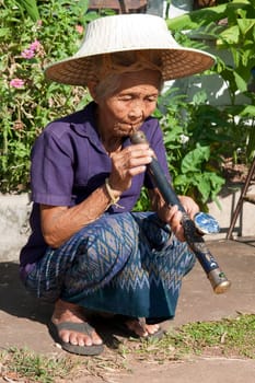 old asian woman with opium pipe