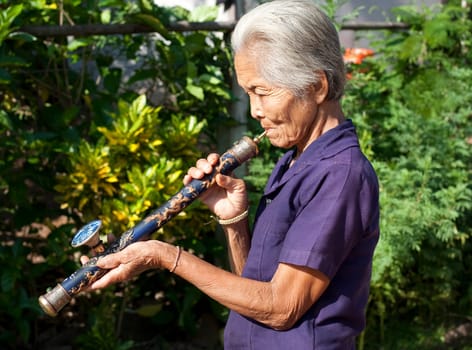 old asian woman with opium pipe