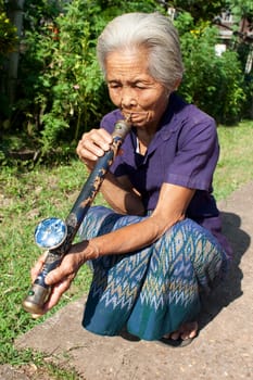 old asian woman with opium pipe