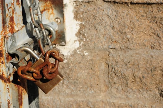 rusty chain and lock against a cement brick wall