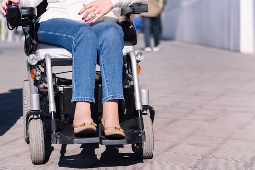 cropped photo of an unrecognizable woman using electric wheelchair at city, concept of urban mobility for people with disability, copy space for text