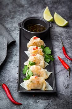 Asian dumplings with soy sauce, chili peppers and herbs