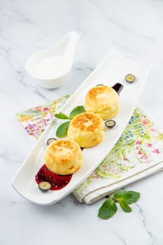 lush and tall cheesecakes with jam and mint on a white plate