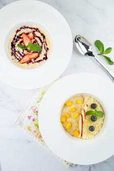 porridge with strawberries, mint and berry jam in a white plate