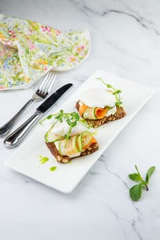 canapes on black bread with cheese, red fish, herbs and cucumber